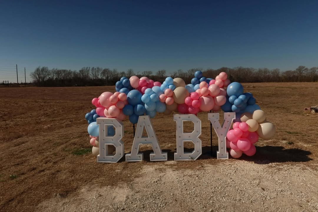 Balloon garland arch set up outdoors for a gender-reveal celebration