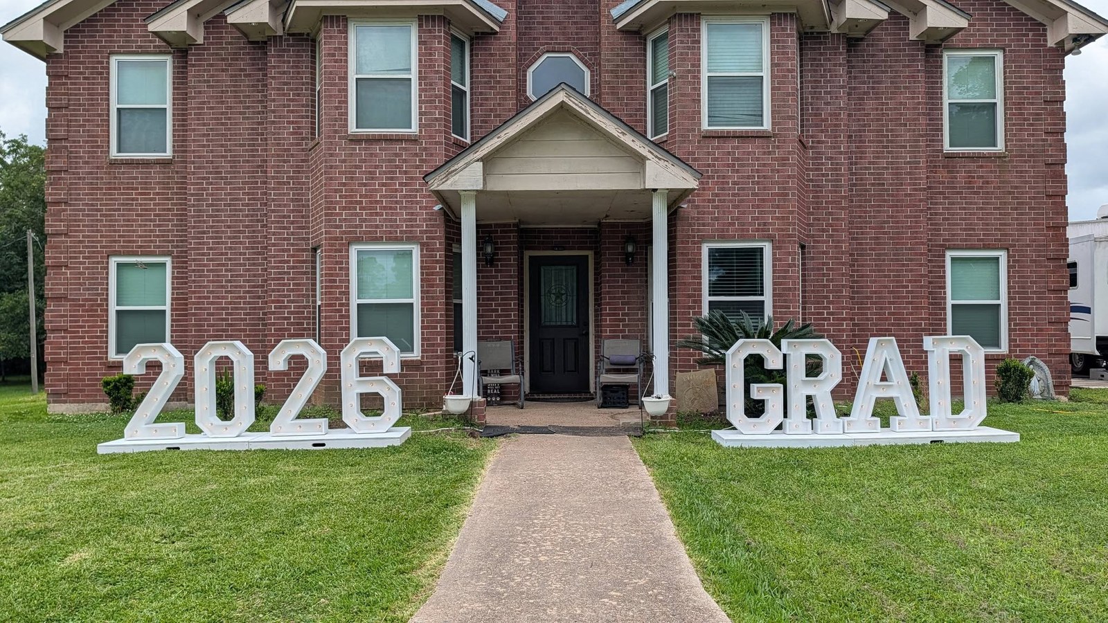 Illuminated marquee number 2026 on a lawn for a graduation celebration
